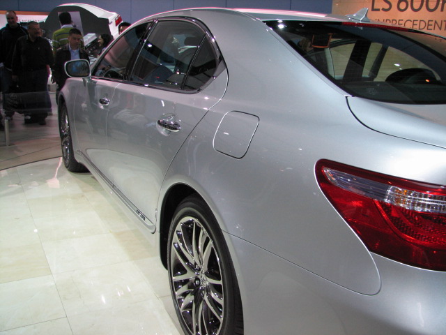 silver car displayed in a showroom on white tiled floor