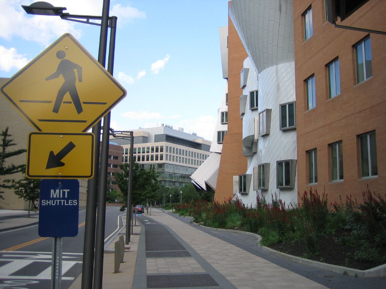 a pedestrian crossing sign on a sidewalk next to two buildings