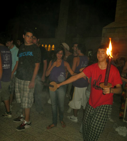 people gather around while holding torches in each hand