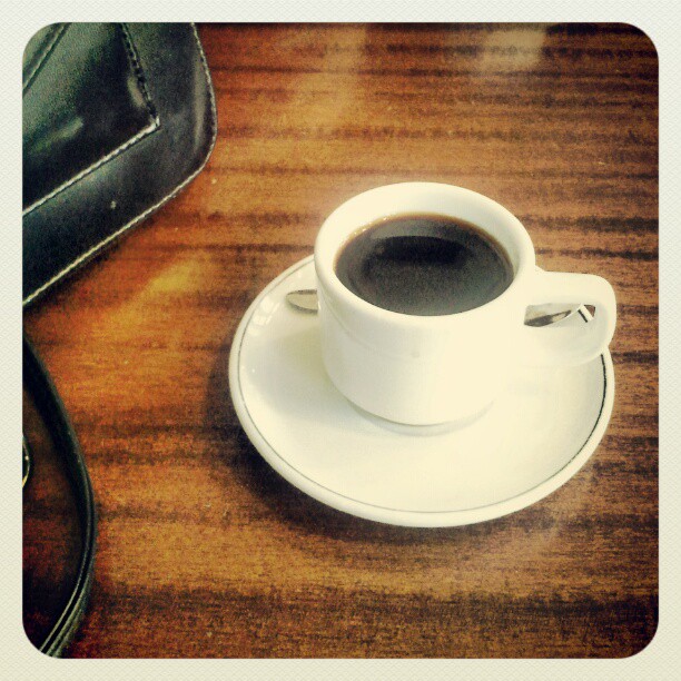 cup of black coffee on a saucer with an eyeglass holder