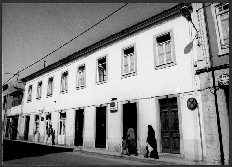 black and white pograph of people walking by a building