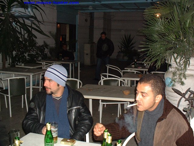 two men sitting at a table smoking cigarettes