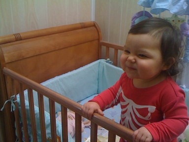 a small girl is standing in her crib
