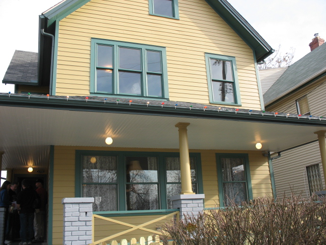 a house has yellow siding and green trim and lights