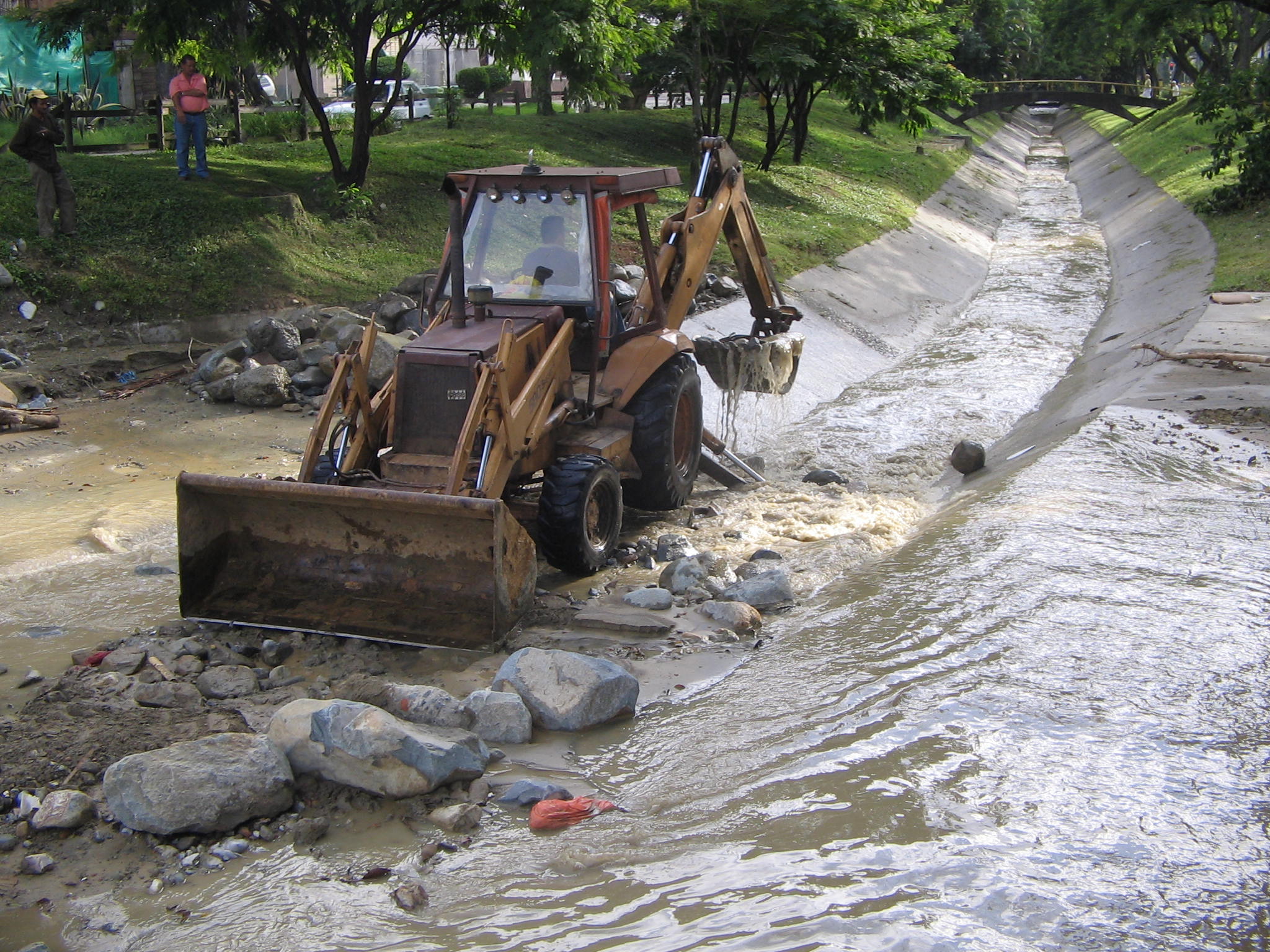 an old bulldozer drives through the river to get to a spot where the water is draining up