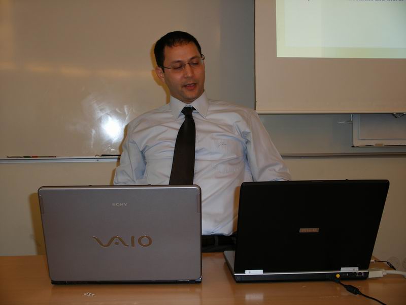 a man sitting at a table in front of two laptop computers