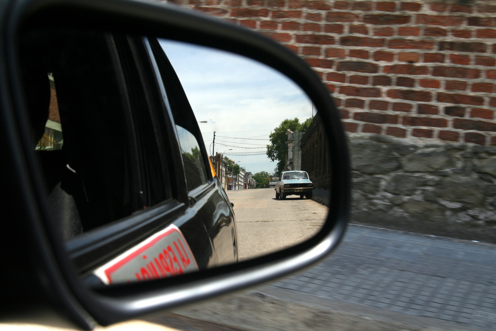 a side mirror is showing a view of a car in the road
