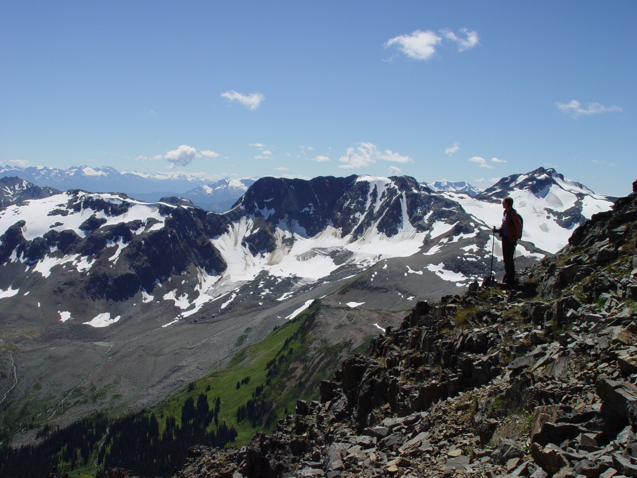 a man standing on the edge of a mountain looking at the snowy mountains