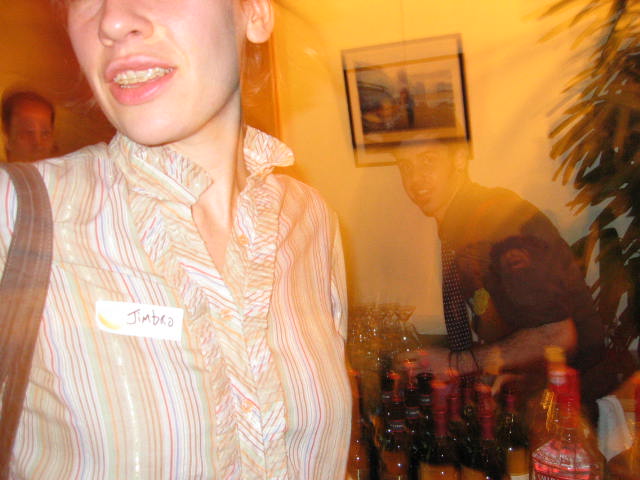 the woman is smiling for the camera near many bottles of alcohol