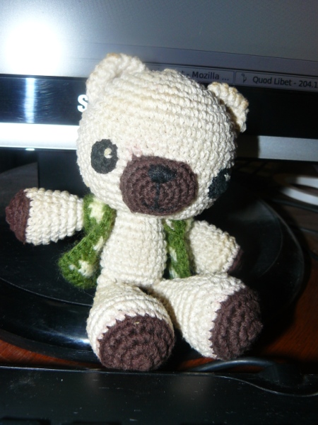 a crocheted teddy bear sitting on top of a plate