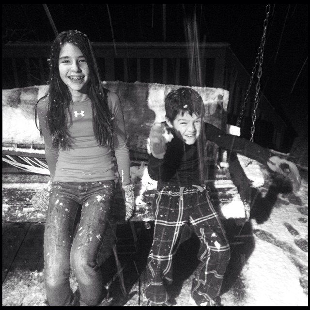 two people standing next to each other in front of a swing