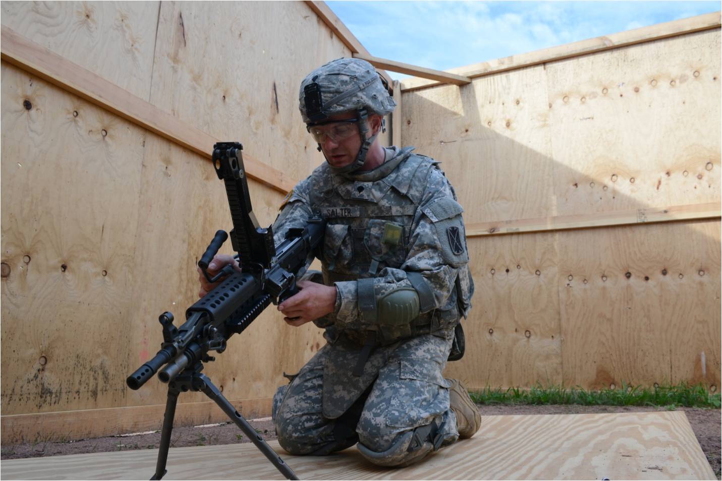 the soldier in camouflage is squatting while holding an ar - pylon