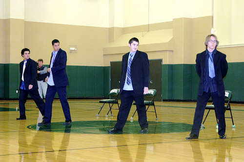 three men are walking together on a hard wood floor
