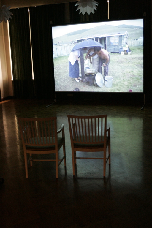chairs are set up in front of an outdoor projector screen