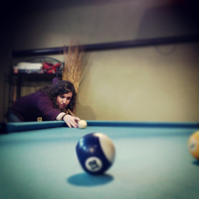 a woman leans over a pool table to play billiard