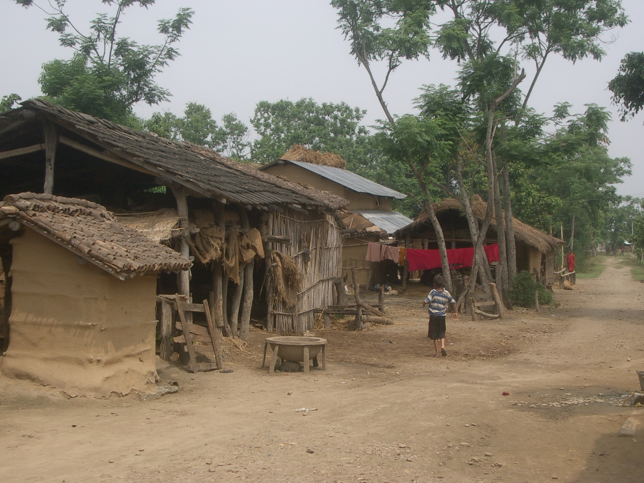 a person walking down a dirt road by some huts