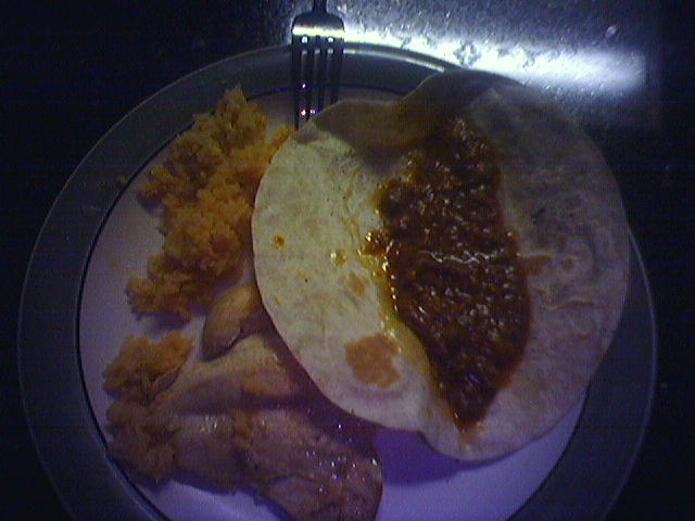 the plate holds some tacos, beans and shrimp