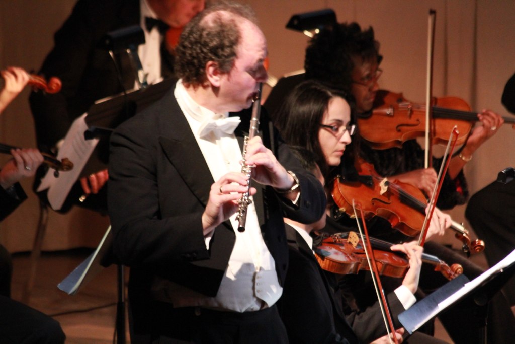 a conductor is playing the flute in a orchestra