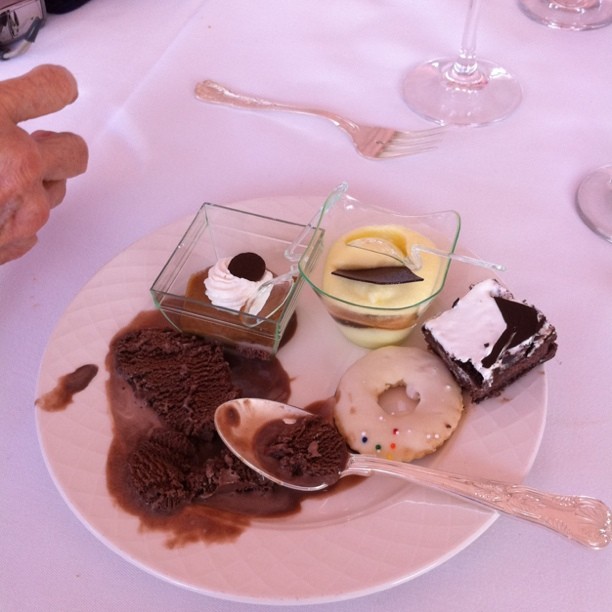 some desserts are on a white plate with glasses and a person's hand