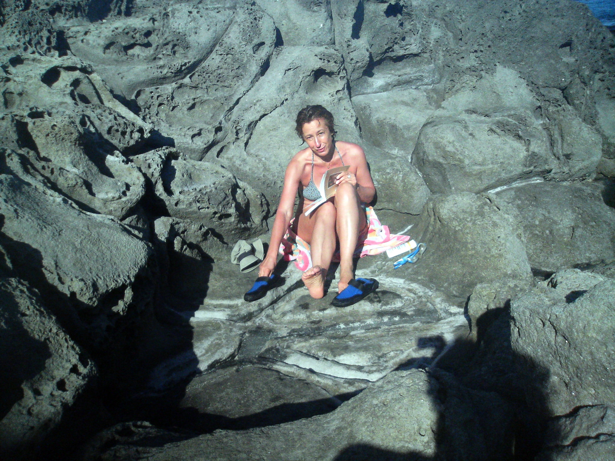 a woman sitting on a rock in her bathing suit