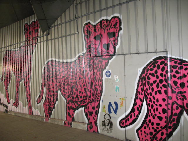 a wall covered in pink graffiti with cheetah and other animals on it