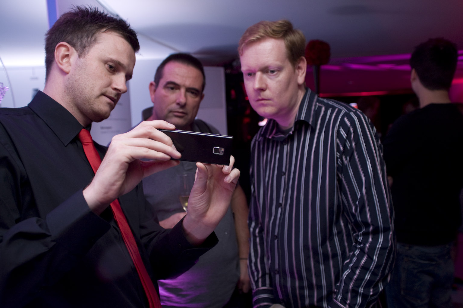 two men holding a phone are standing in a room