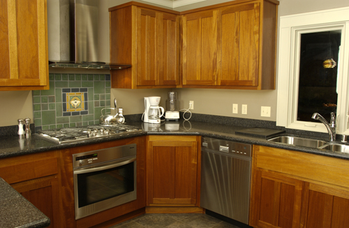an empty kitchen with wood cabinetry and grey countertops