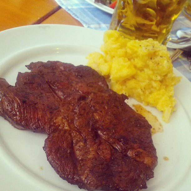 meat and sides on a plate with two beers