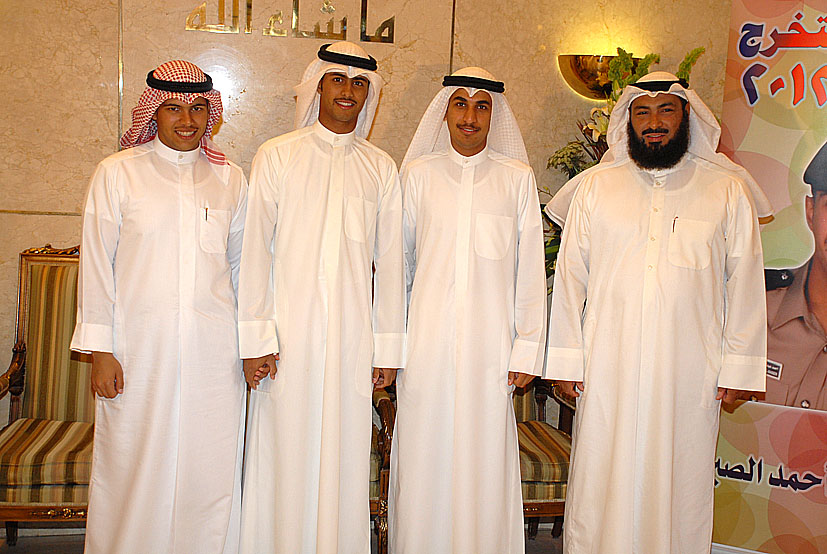 a group of five men standing next to each other in front of a sign