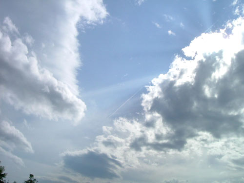 blue sky filled with white clouds and a plane in the distance