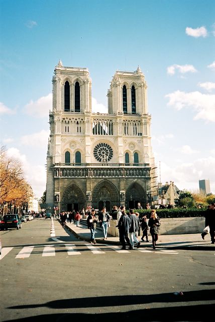 people are walking down the road in front of a large cathedral