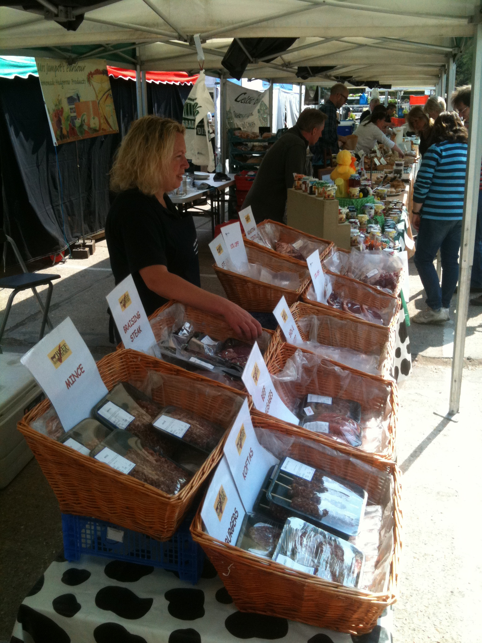 a woman is standing behind a display under an awning at a market