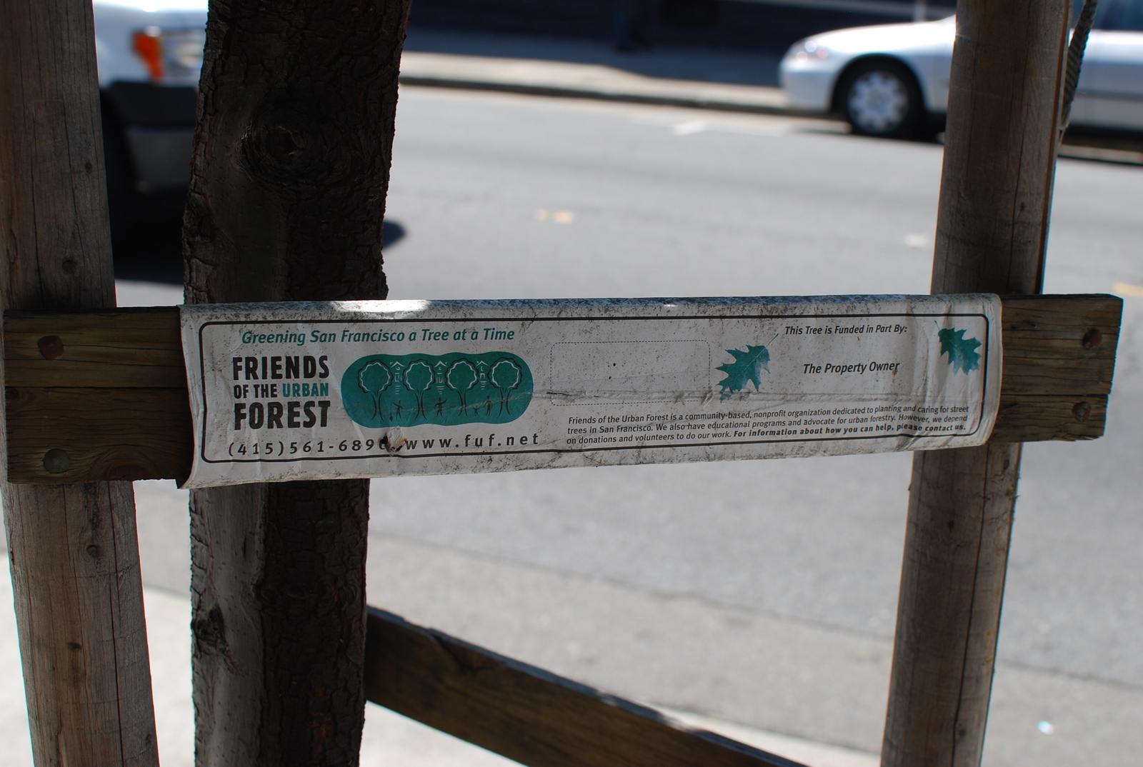 a sign attached to a fence on a sidewalk