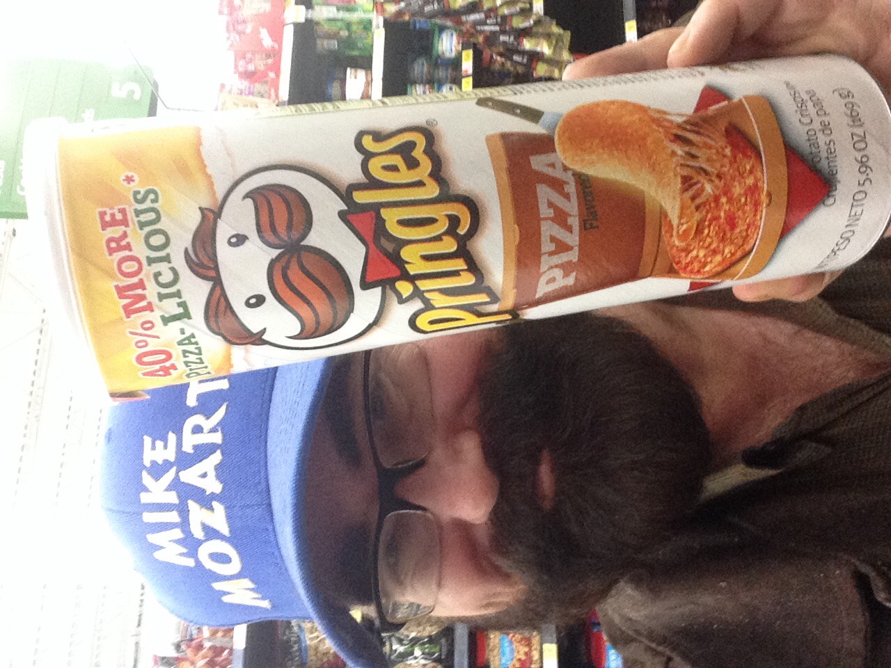 a man wearing a hat and glasses holding a box of pringles