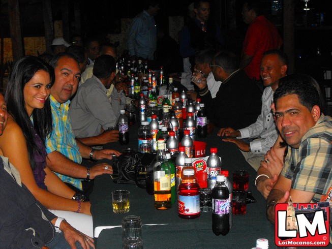 a table covered with people sitting around bottles of beer