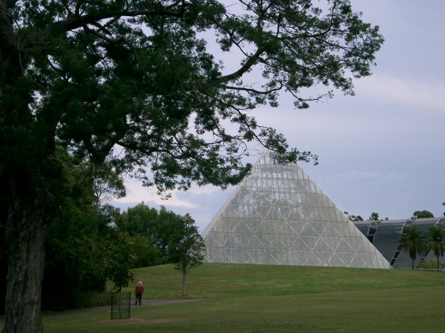 two pyramid shaped structures sit in a green park