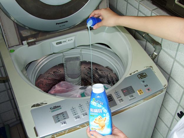 a person is cleaning a washing machine with laundry detergent