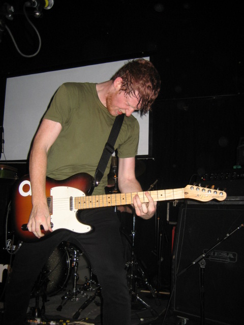 a guy playing a guitar on stage in a band