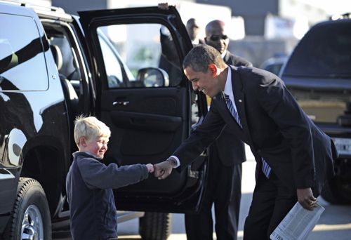 a little boy shaking hands with another man next to him
