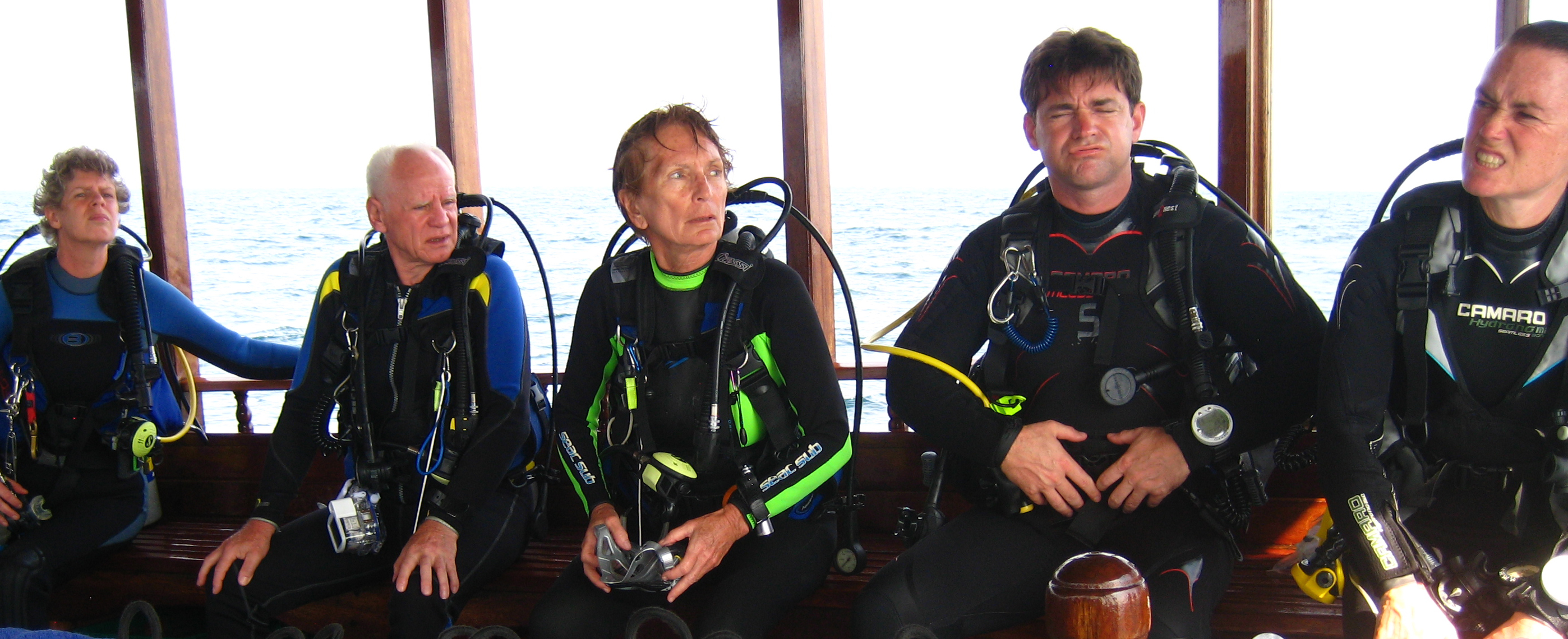 a group of men wearing scuba gear sitting on a bench next to the ocean