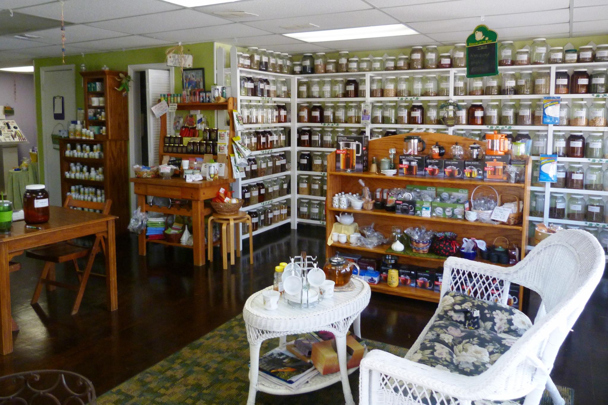 a room full of wicker chairs and tables and shelves with jars on them