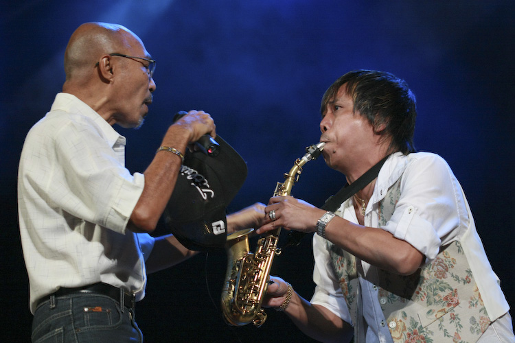 two men are playing instruments in front of blue lights