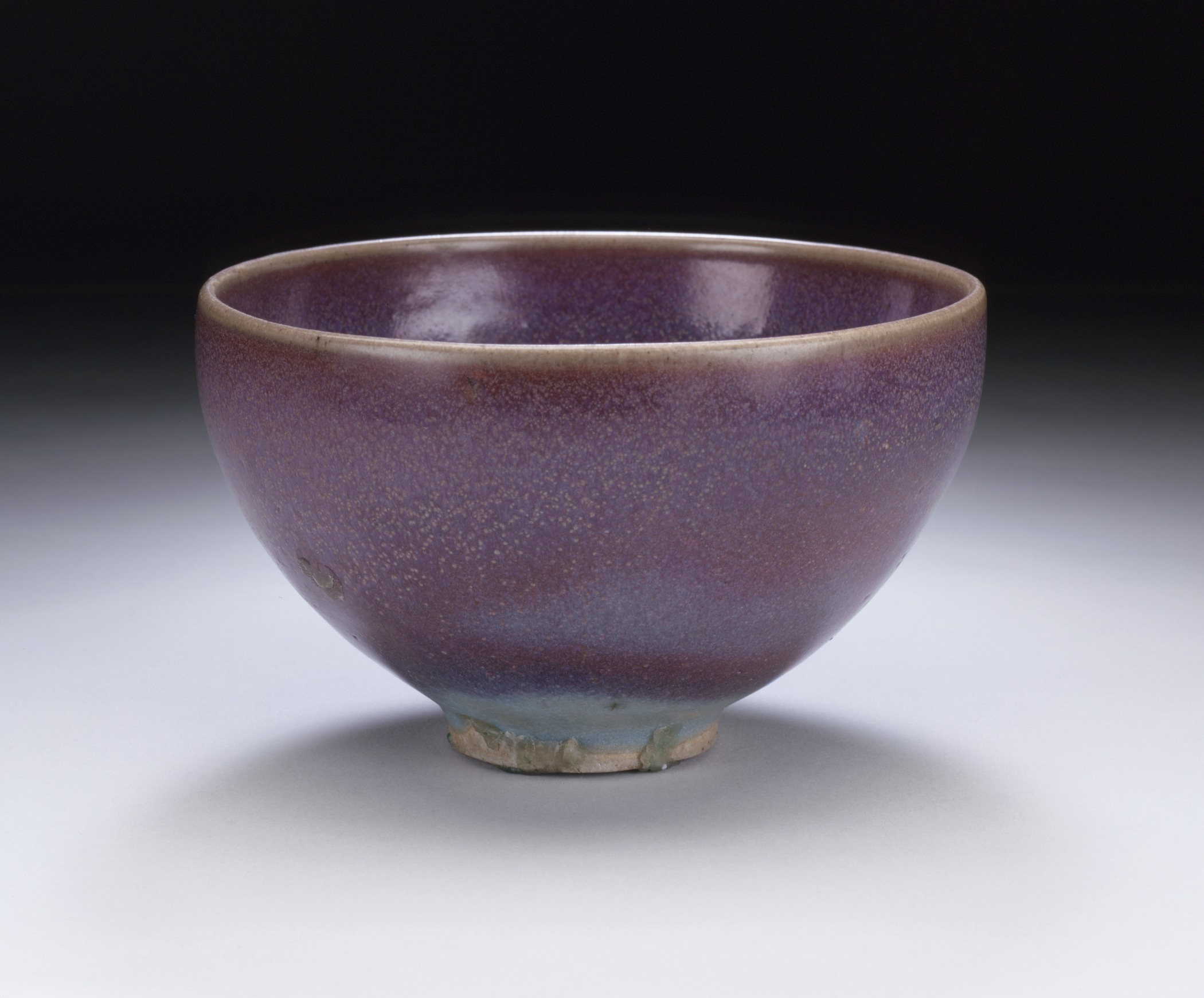 a purple bowl with blue rim against a black background