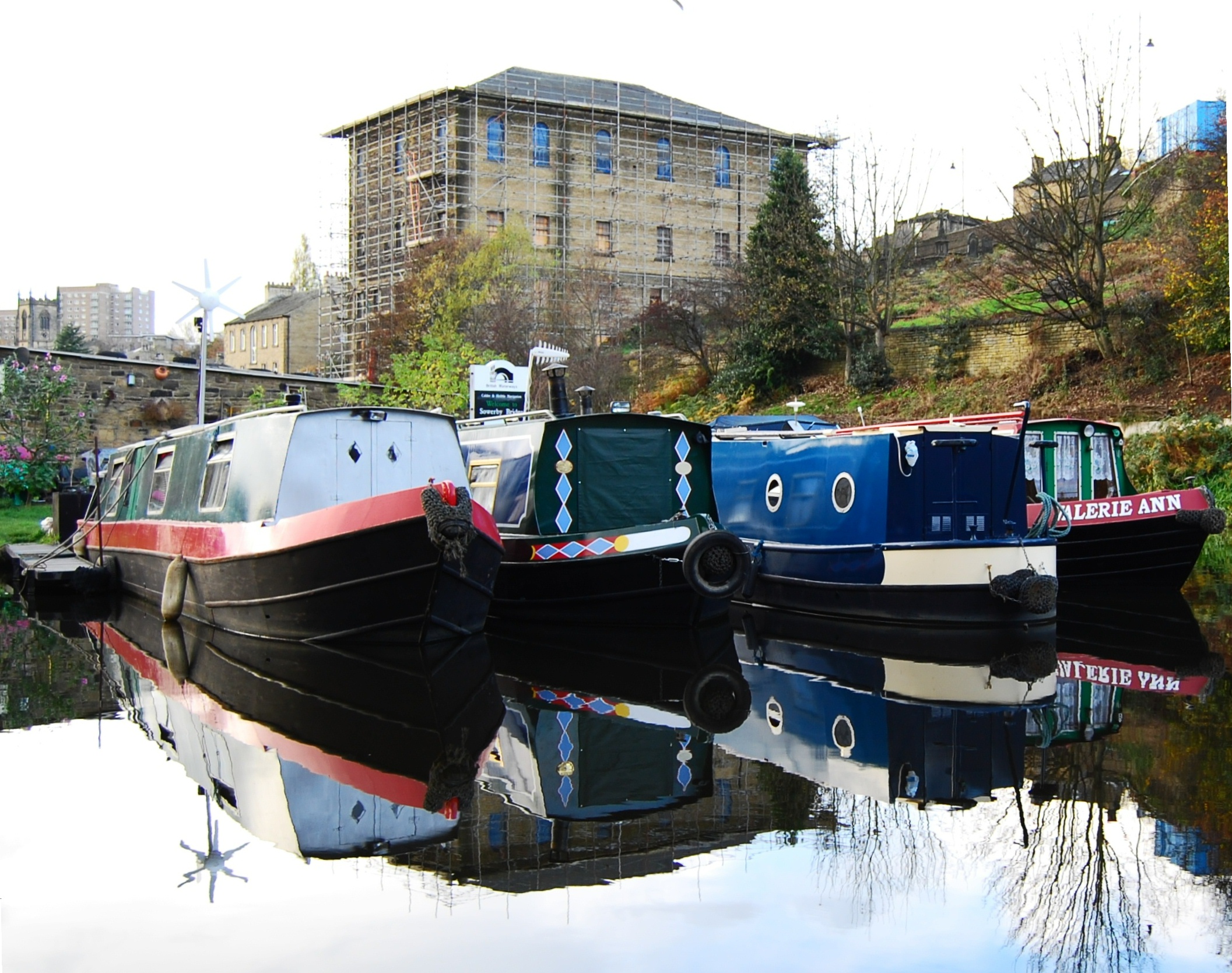 three tug boats docked on the side of a river