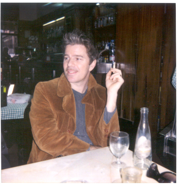 a man smokes with a bottle of alcohol in front of him