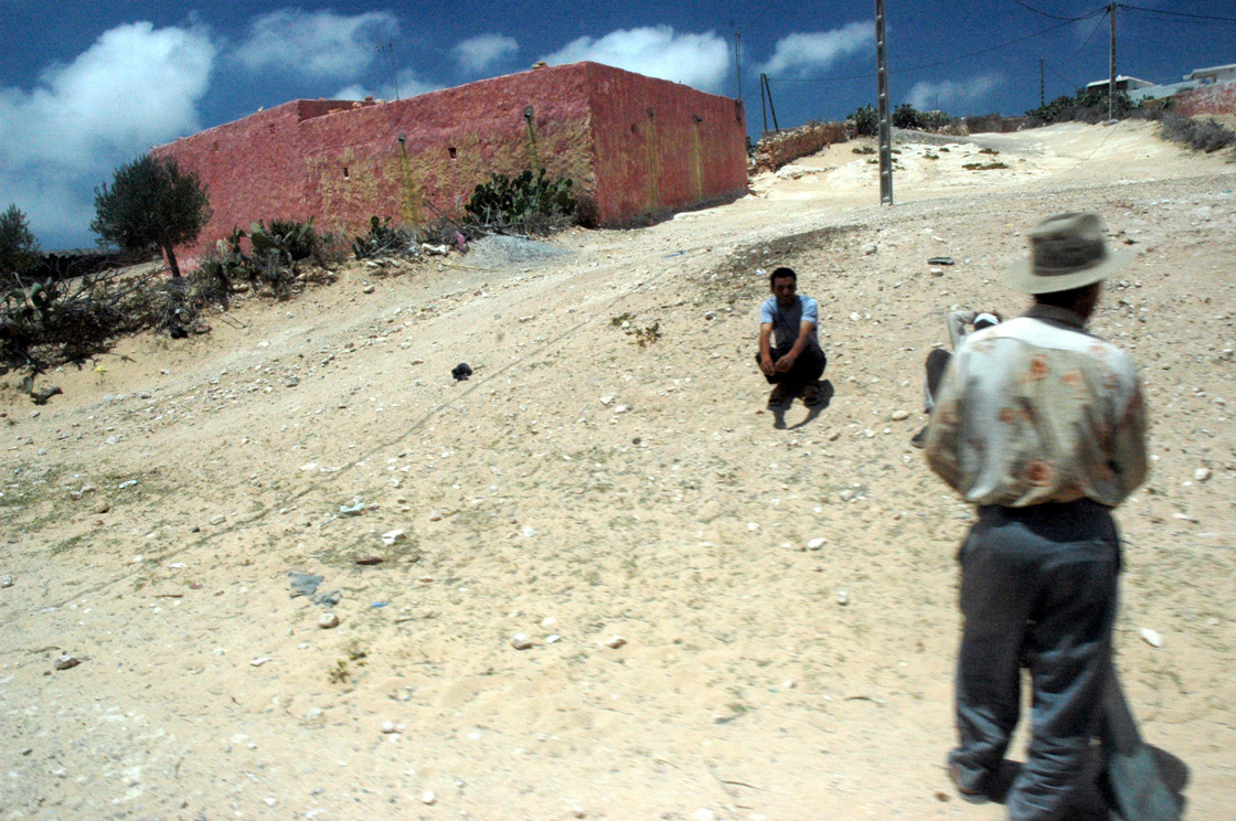 two people are playing frisbee in the dirt