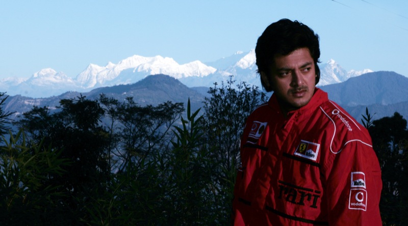 a man in a red jacket standing in front of mountains