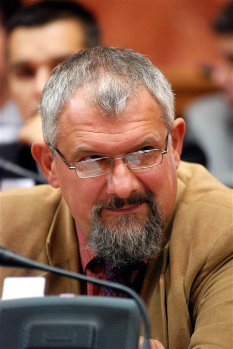 an older man with a gray beard and glasses sitting next to a microphone