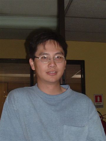 the young man wearing glasses is standing near a laptop