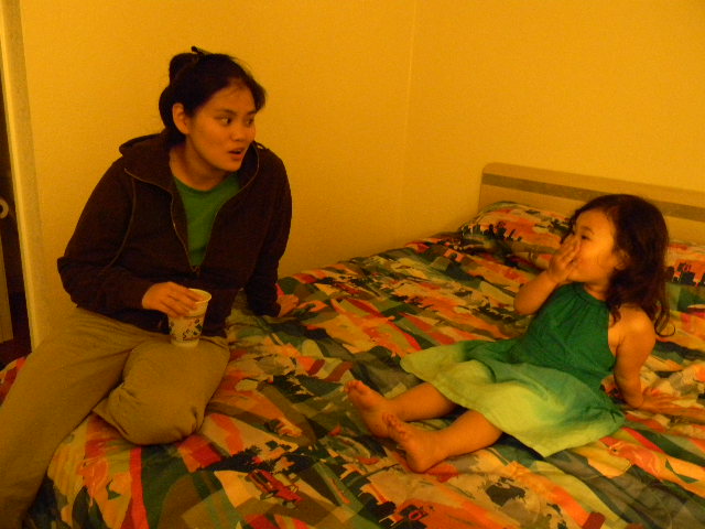 a woman sitting on the bed with a little girl